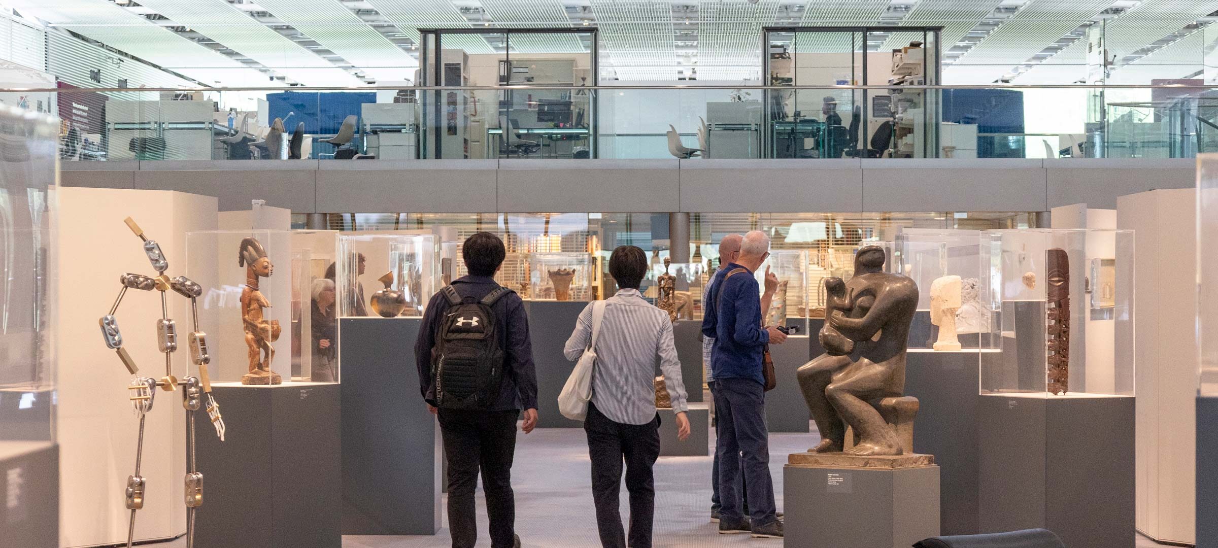 A few visitors seen from behind walking through The Living Area at the Sainsbury Centre Art Museum.