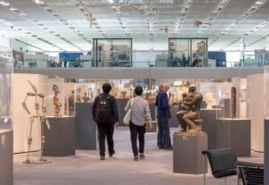 A few visitors seen from behind walking through The Living Area at the Sainsbury Centre Art Museum.