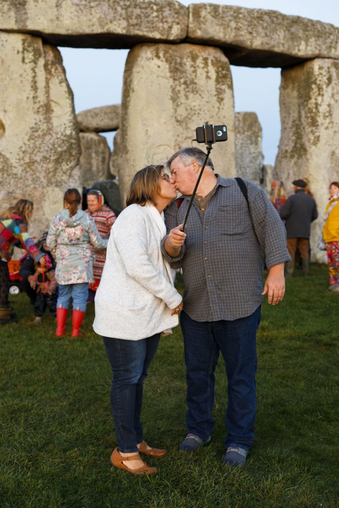 Martin Parr, photograph taken at Stonehenge, Wiltshire, during the autumn equinox, 2019. © Martin Parr/Magnum Photos Photograph of a couple kissing in front of the historical site of Stongehenge, United Kingdom