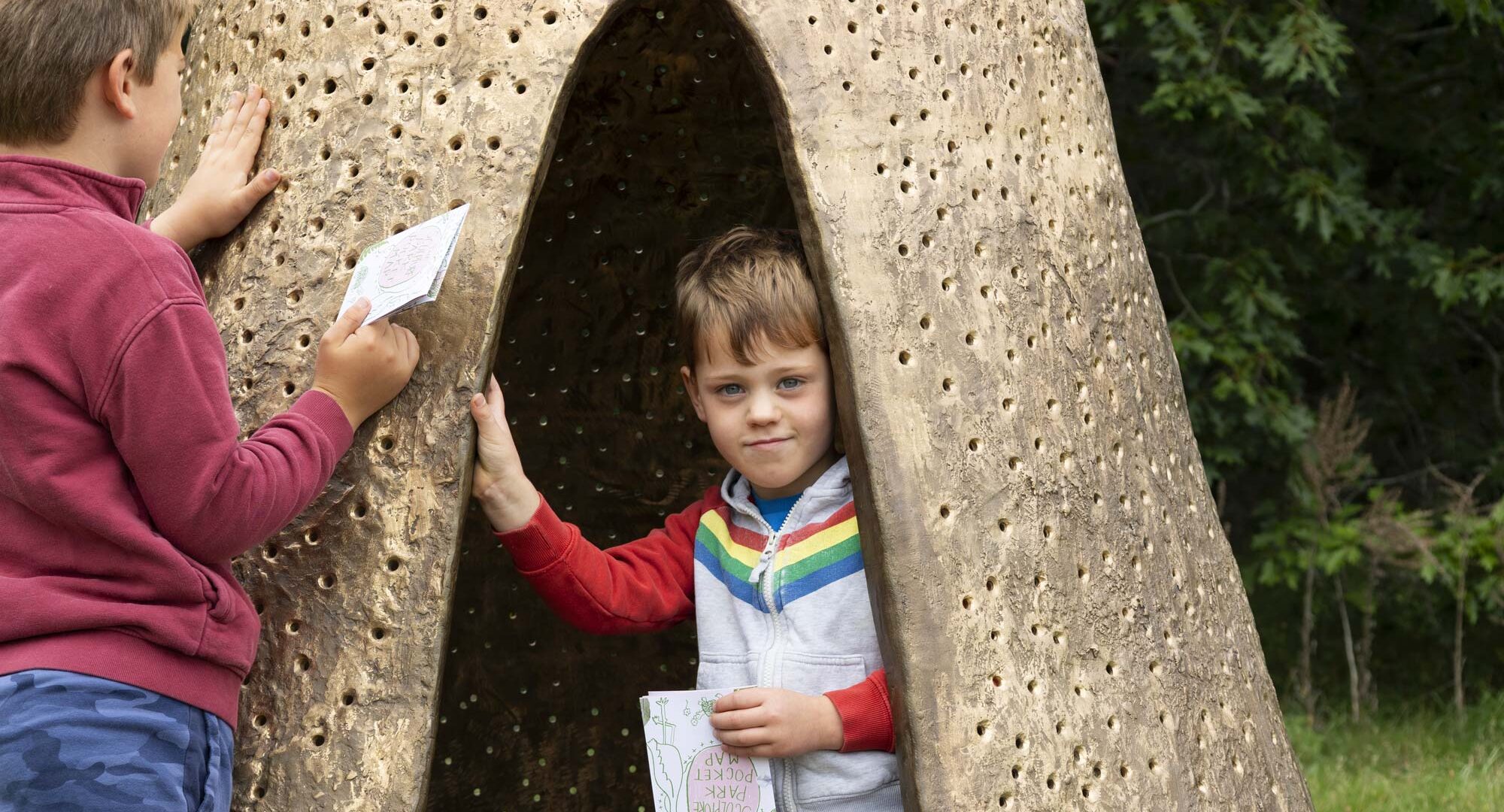 Two young boys exploring a large bronze sculpture outdoors in a sculpture park