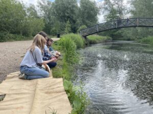 Young people fish in the river with a bridge in the background