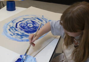 Young girl making a blue abstract painting