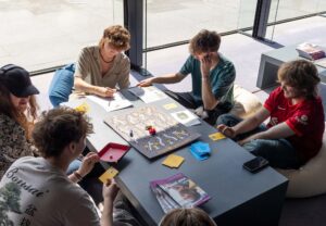A group of five young people sitting around a table playing a board game at the Sainsbury Centre in Norwich