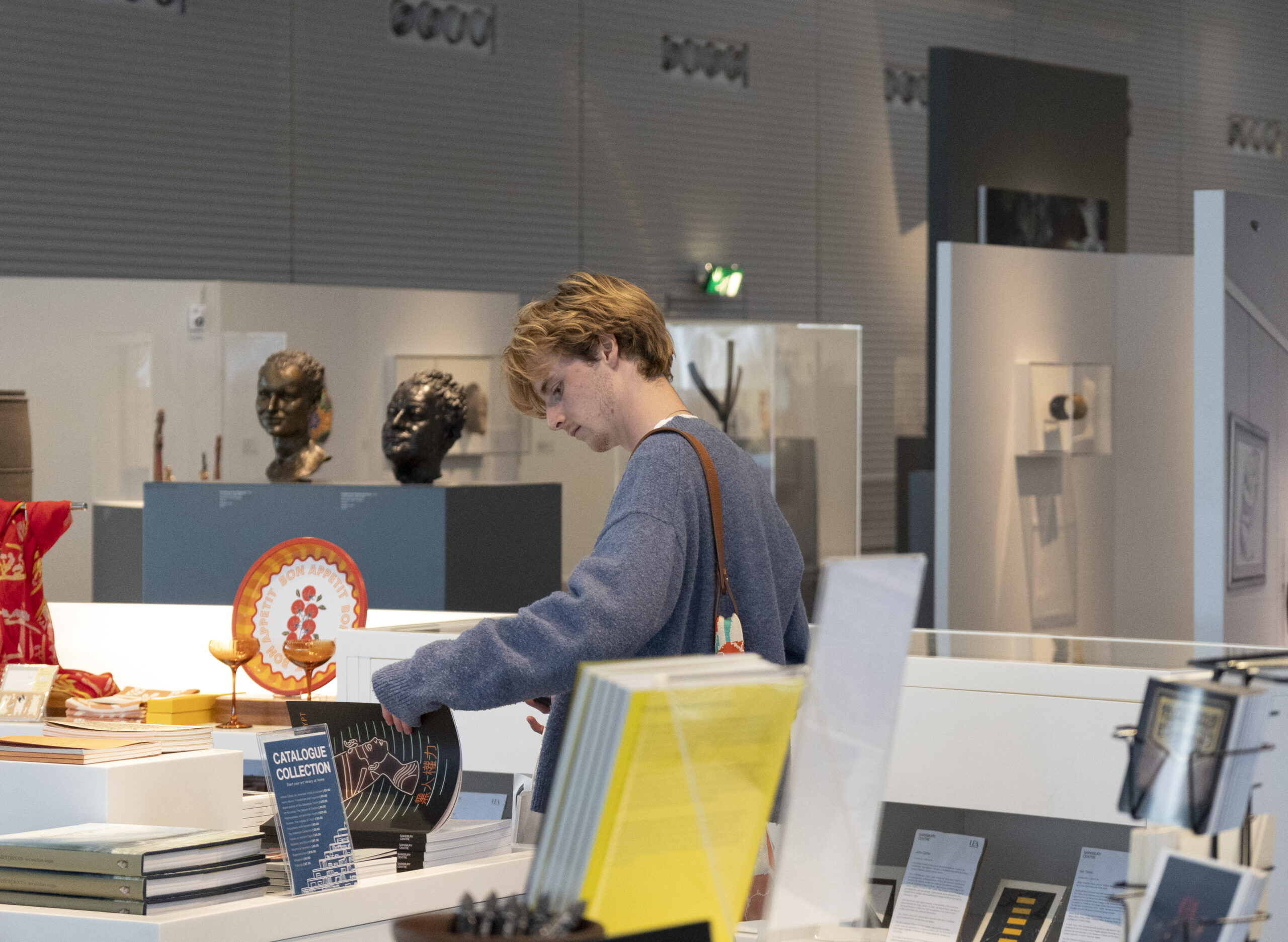 Student Social_Photo Kate Wolstenholme_11 A young boy with blonde hair and grey jumper shopping in the Sainsbury Centre shop