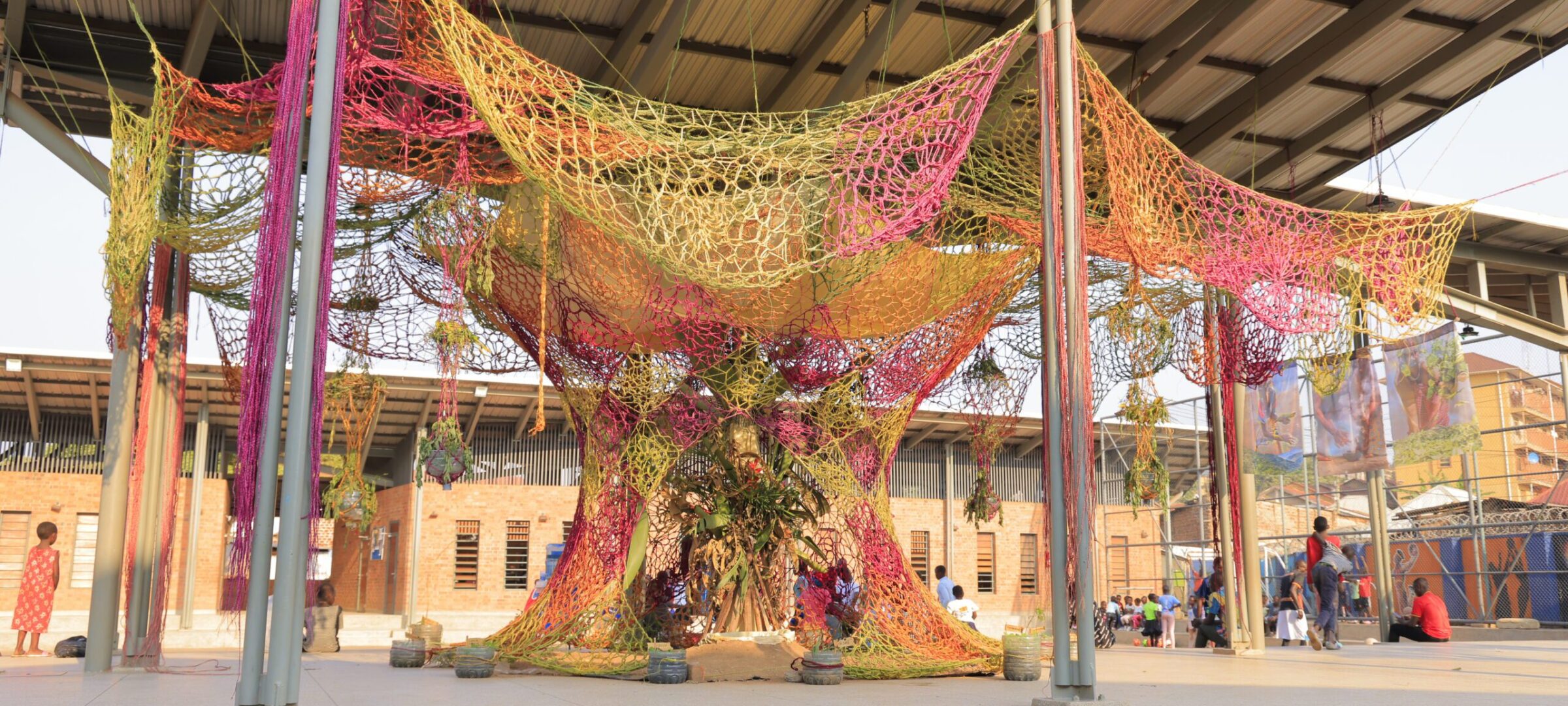 A massive colourful installation in a playground made from woven hand dyed sisal rope