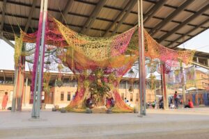 A massive colourful installation in a playground made from woven hand dyed sisal rope